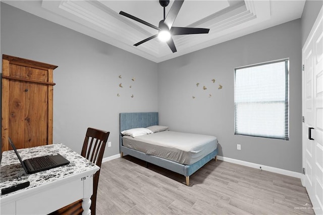 bedroom featuring ceiling fan, light hardwood / wood-style flooring, and a tray ceiling