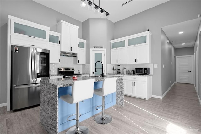 kitchen with sink, white cabinetry, an island with sink, stainless steel appliances, and stone countertops