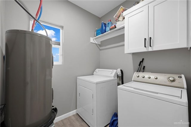 clothes washing area featuring cabinets, electric water heater, light hardwood / wood-style flooring, and washing machine and clothes dryer