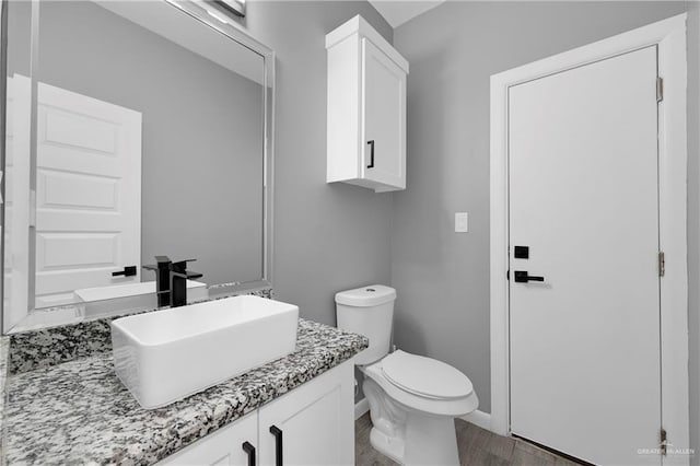 bathroom featuring toilet, vanity, and hardwood / wood-style flooring