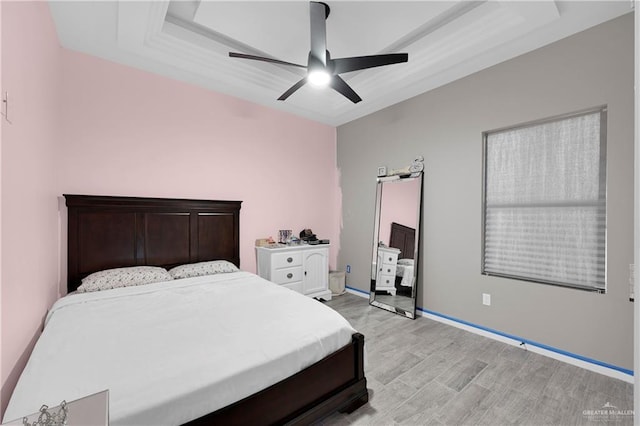 bedroom featuring ceiling fan, light hardwood / wood-style floors, and a raised ceiling