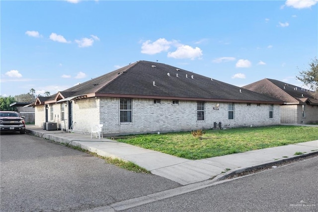 view of side of home with central AC and a yard