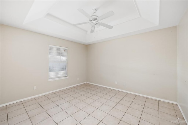 tiled empty room featuring a tray ceiling and ceiling fan