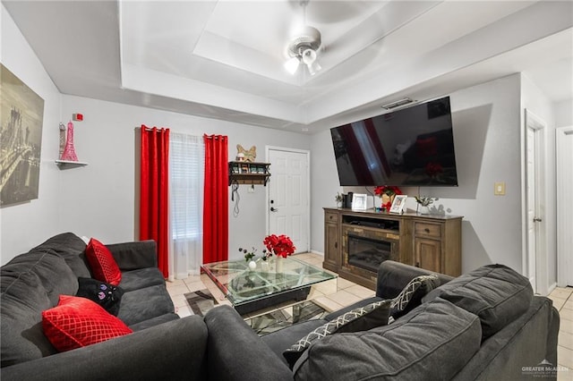 living room featuring light tile patterned floors, a tray ceiling, and ceiling fan