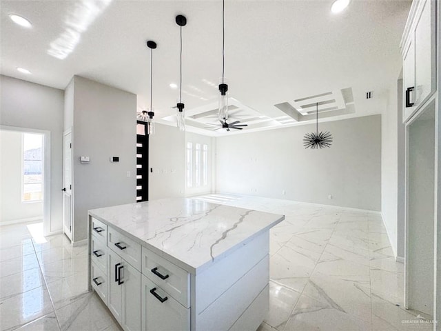 kitchen featuring plenty of natural light, light stone countertops, a center island, and white cabinets