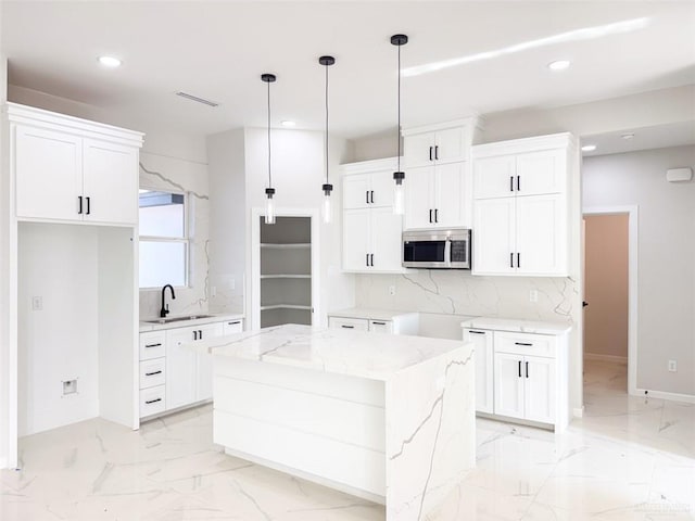 kitchen featuring a center island, white cabinets, light stone counters, and decorative light fixtures