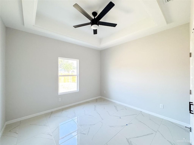 spare room with ceiling fan and a tray ceiling