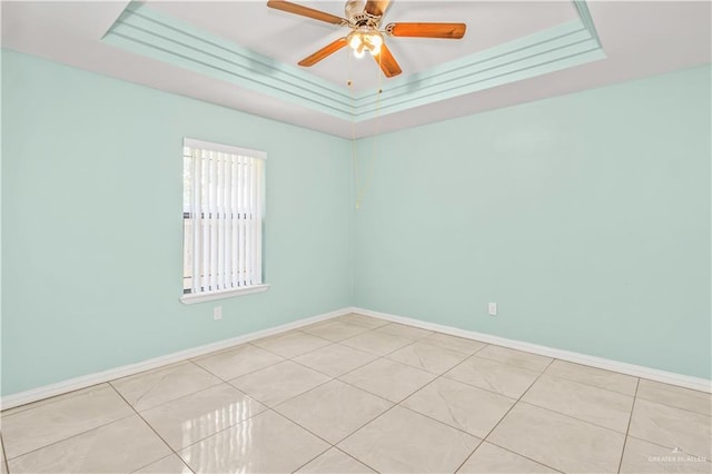 spare room featuring a raised ceiling, ceiling fan, ornamental molding, and light tile patterned flooring