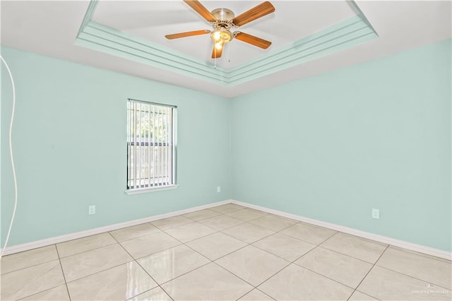 tiled spare room featuring a tray ceiling and ceiling fan