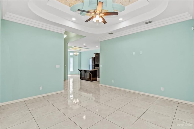 empty room with ceiling fan with notable chandelier, a tray ceiling, and crown molding