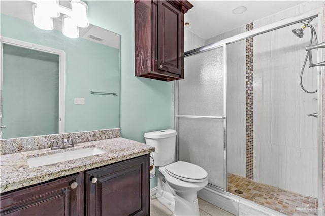 bathroom with tile patterned floors, vanity, a shower with shower door, and toilet