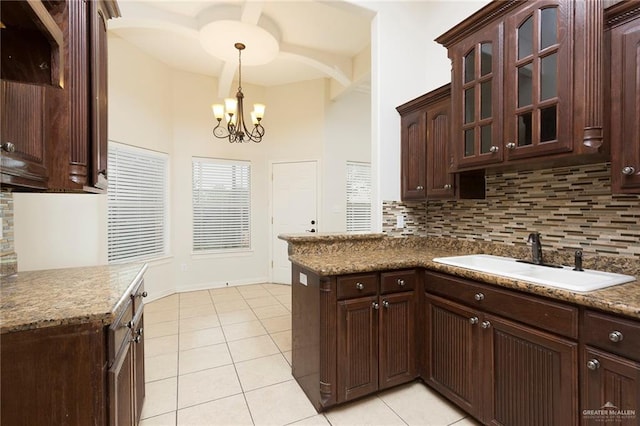 kitchen with kitchen peninsula, sink, light tile patterned floors, decorative light fixtures, and an inviting chandelier