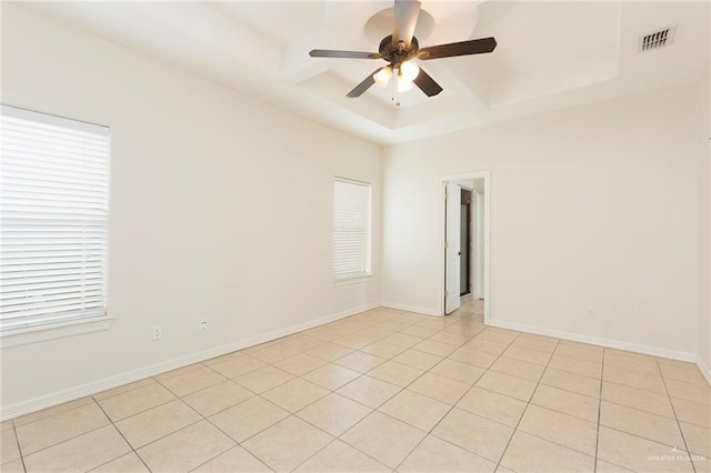 spare room with a tray ceiling, ceiling fan, and light tile patterned flooring