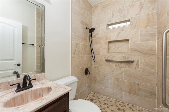 bathroom featuring vanity, toilet, and tiled shower