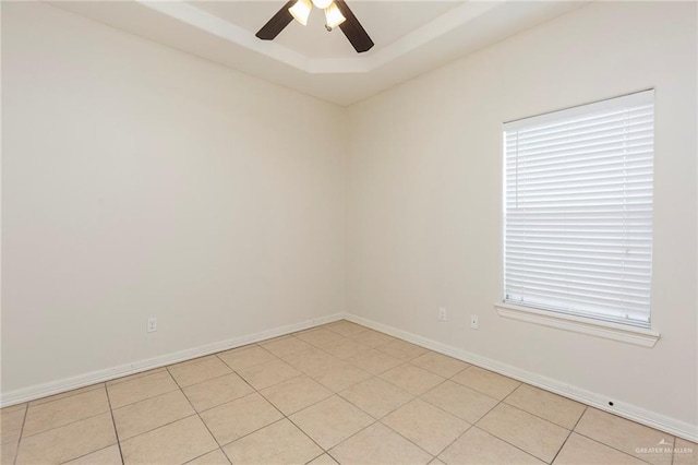 tiled spare room with a tray ceiling and ceiling fan