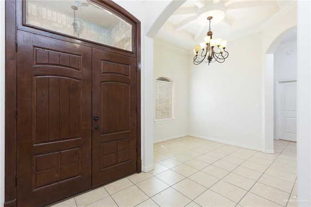 tiled foyer entrance with a chandelier and ornamental molding