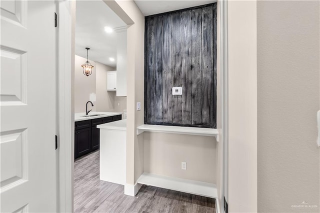 interior space with white cabinets, pendant lighting, light hardwood / wood-style flooring, and sink