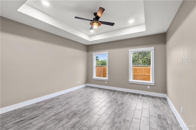 empty room featuring a tray ceiling and ceiling fan