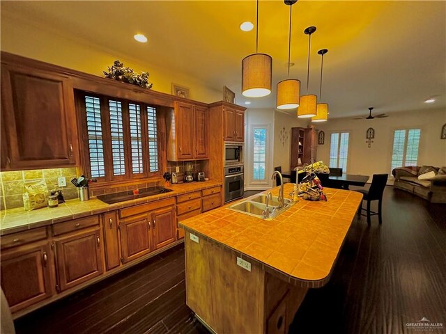 kitchen featuring a sink, stainless steel appliances, tile countertops, recessed lighting, and open floor plan