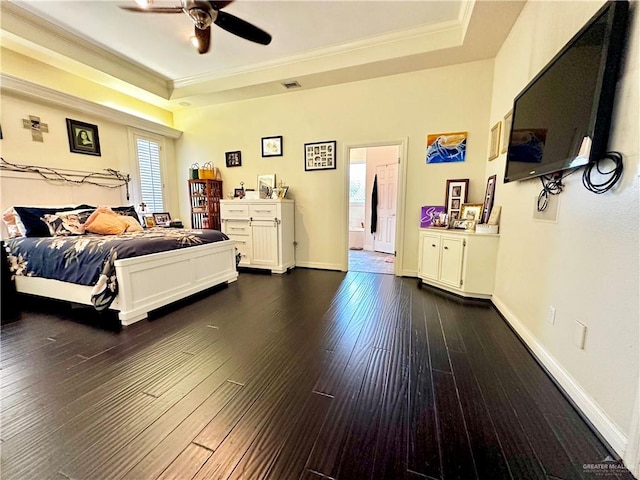 bedroom featuring crown molding, dark wood-type flooring, baseboards, a raised ceiling, and visible vents