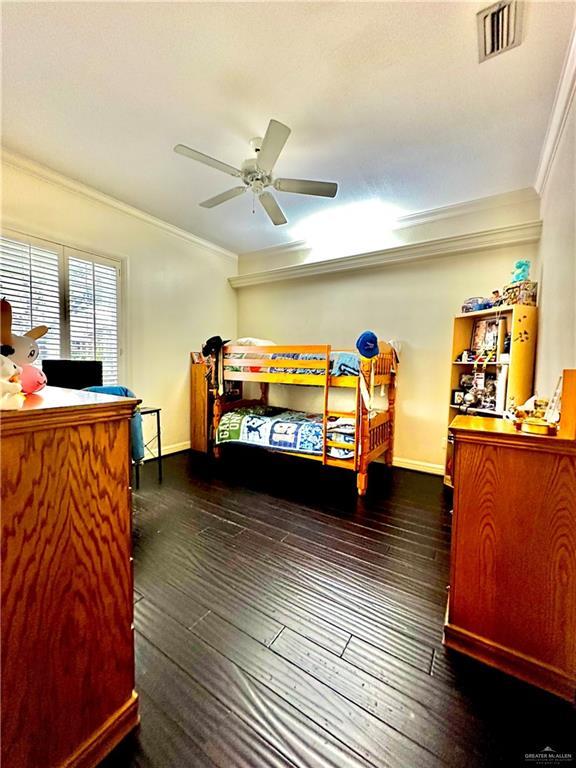 bedroom with baseboards, ornamental molding, dark wood finished floors, and ceiling fan