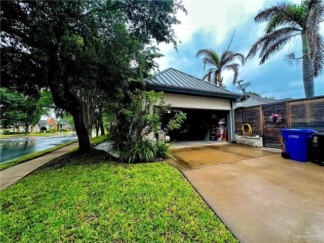 view of front facade featuring fence, metal roof, an attached garage, concrete driveway, and a front yard