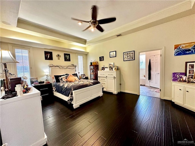 bedroom with dark wood-type flooring, visible vents, crown molding, ceiling fan, and a tray ceiling