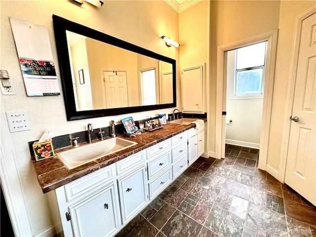 full bathroom featuring a sink, double vanity, baseboards, and stone tile flooring