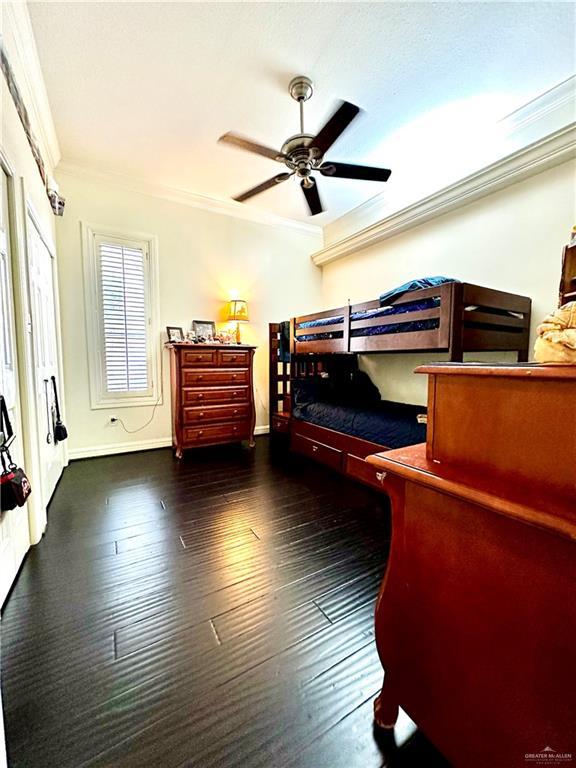 bedroom with baseboards, ornamental molding, hardwood / wood-style floors, and ceiling fan