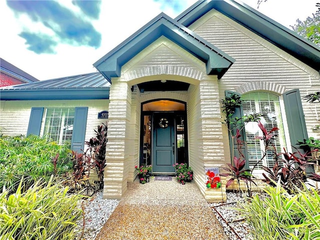 view of exterior entry featuring brick siding and metal roof