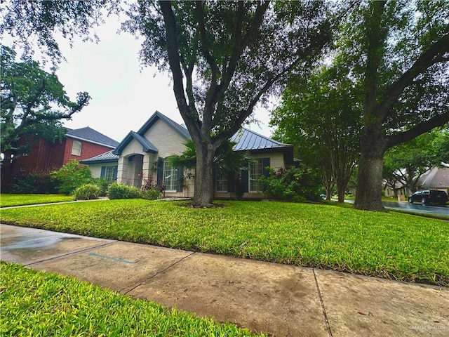 ranch-style home featuring a front yard, a standing seam roof, and metal roof