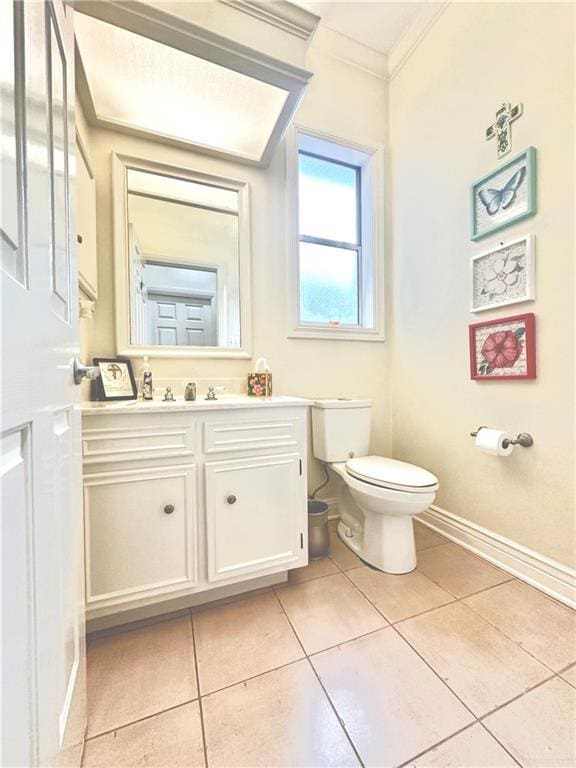 bathroom featuring toilet, vanity, ornamental molding, tile patterned flooring, and baseboards