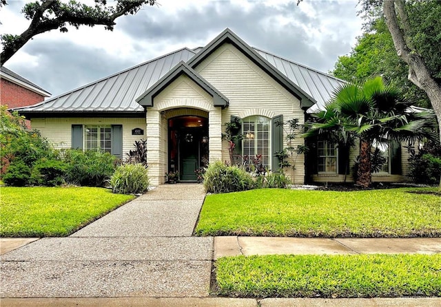 view of front of house featuring metal roof, a front yard, and a standing seam roof