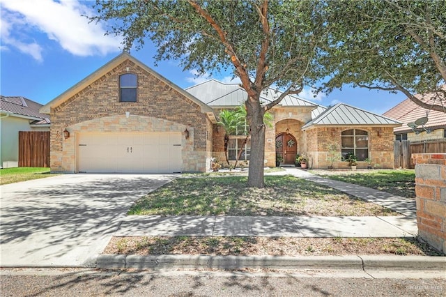 2504 Wernecke Ave, Mission, TX 78574 - view of front facade featuring a standing seam roof, concrete driveway, a garage, stone siding, and metal roof