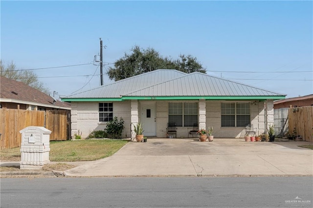 ranch-style house featuring metal roof, a front lawn, and fence