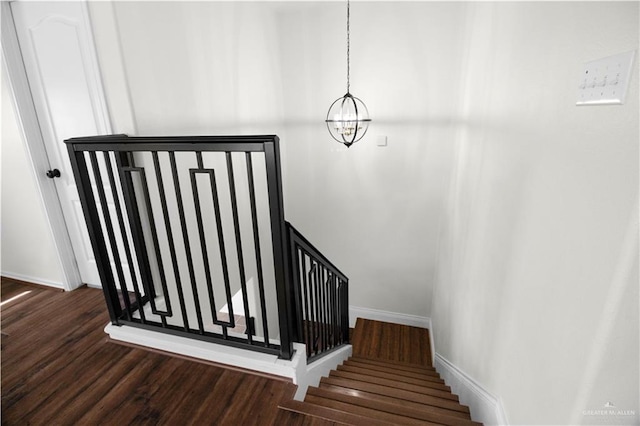 staircase featuring hardwood / wood-style floors and an inviting chandelier