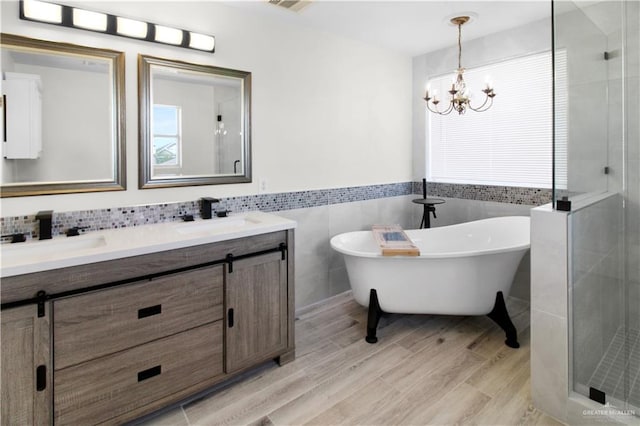 bathroom with a chandelier, wood-type flooring, tile walls, and plus walk in shower