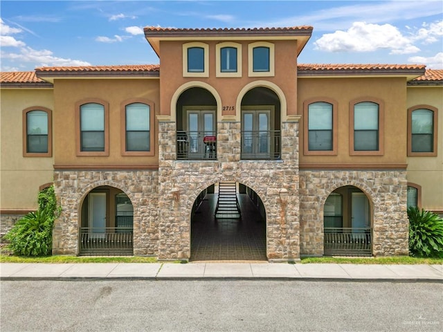 2715 Mimosa St Unit 9, Mission, TX 78572 - view of front of home featuring french doors, stucco siding, a balcony, and stone siding