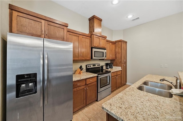2715 Mimosa St Unit 9, Mission, TX 78572 - kitchen with stainless steel appliances, a sink, brown cabinetry, light tile patterned floors, and light stone counters