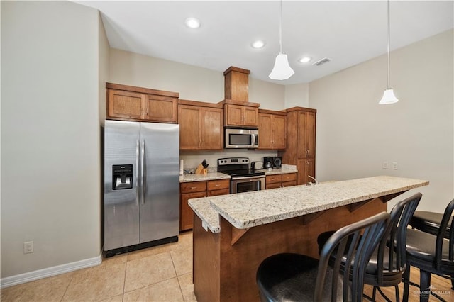 2715 Mimosa St Unit 9, Mission, TX 78572 - kitchen with stainless steel appliances, brown cabinetry, a kitchen bar, hanging light fixtures, and recessed lighting