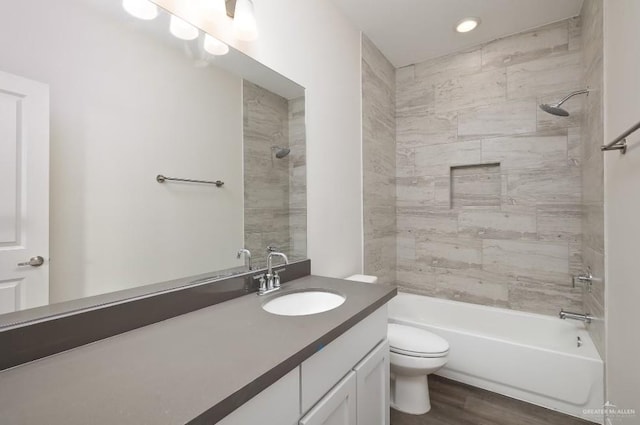 full bathroom featuring hardwood / wood-style flooring, vanity, toilet, and tiled shower / bath combo