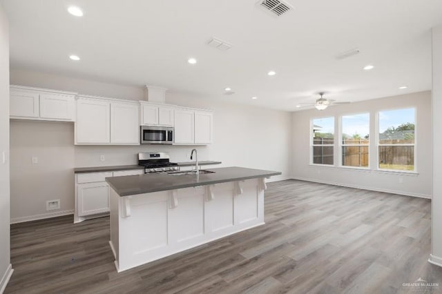 kitchen with sink, a breakfast bar area, appliances with stainless steel finishes, a kitchen island with sink, and white cabinetry