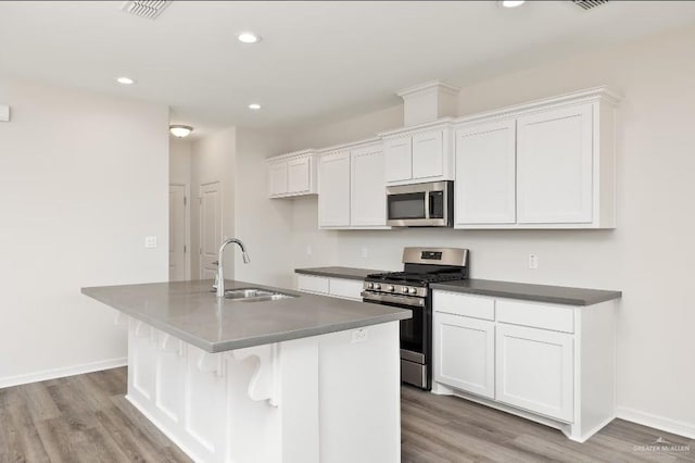 kitchen with appliances with stainless steel finishes, a center island with sink, and white cabinets