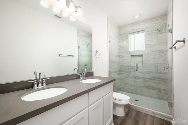 bathroom with hardwood / wood-style flooring, vanity, toilet, and a shower with shower door