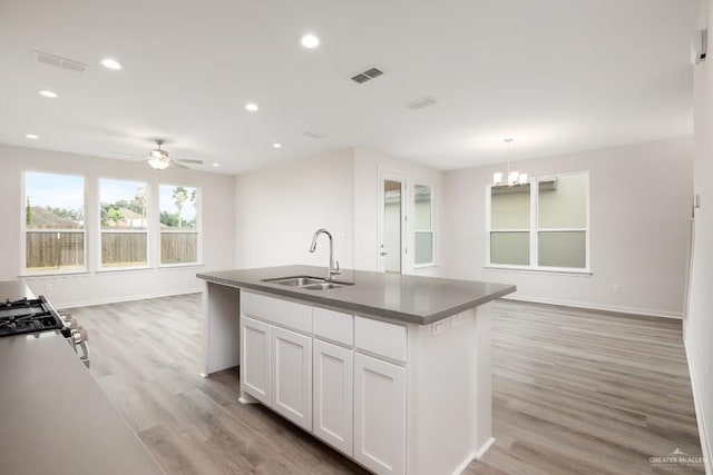 kitchen featuring sink, light hardwood / wood-style flooring, a center island with sink, pendant lighting, and white cabinets