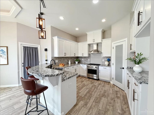 2411 Q St, Hidalgo, TX 78557 - kitchen featuring high end stainless steel range oven, a peninsula, wall chimney range hood, a sink, and wood tiled floors
