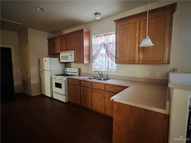 kitchen featuring pendant lighting, dark hardwood / wood-style floors, white appliances, and sink