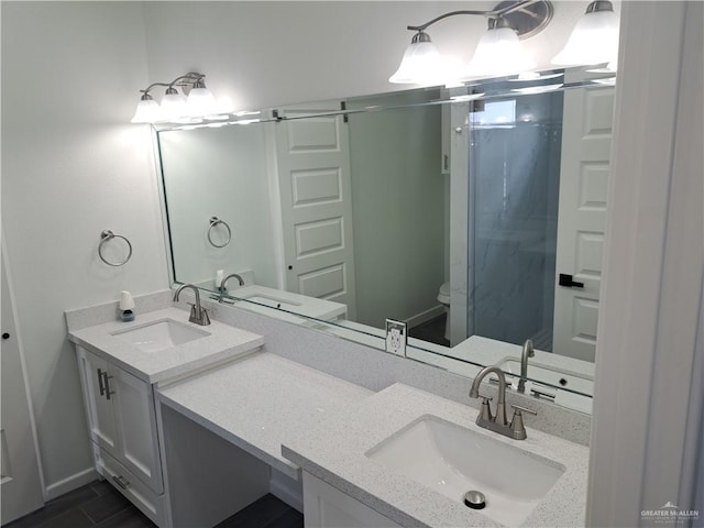 708 E 3rd Ave, Elsa, TX 78543 - bathroom featuring double vanity, a stall shower, toilet, and baseboards