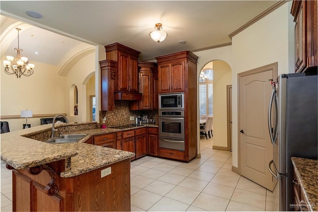 kitchen with pendant lighting, sink, appliances with stainless steel finishes, a notable chandelier, and kitchen peninsula