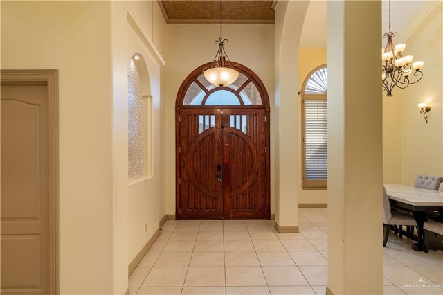 entrance foyer with a towering ceiling, light tile patterned flooring, and a notable chandelier